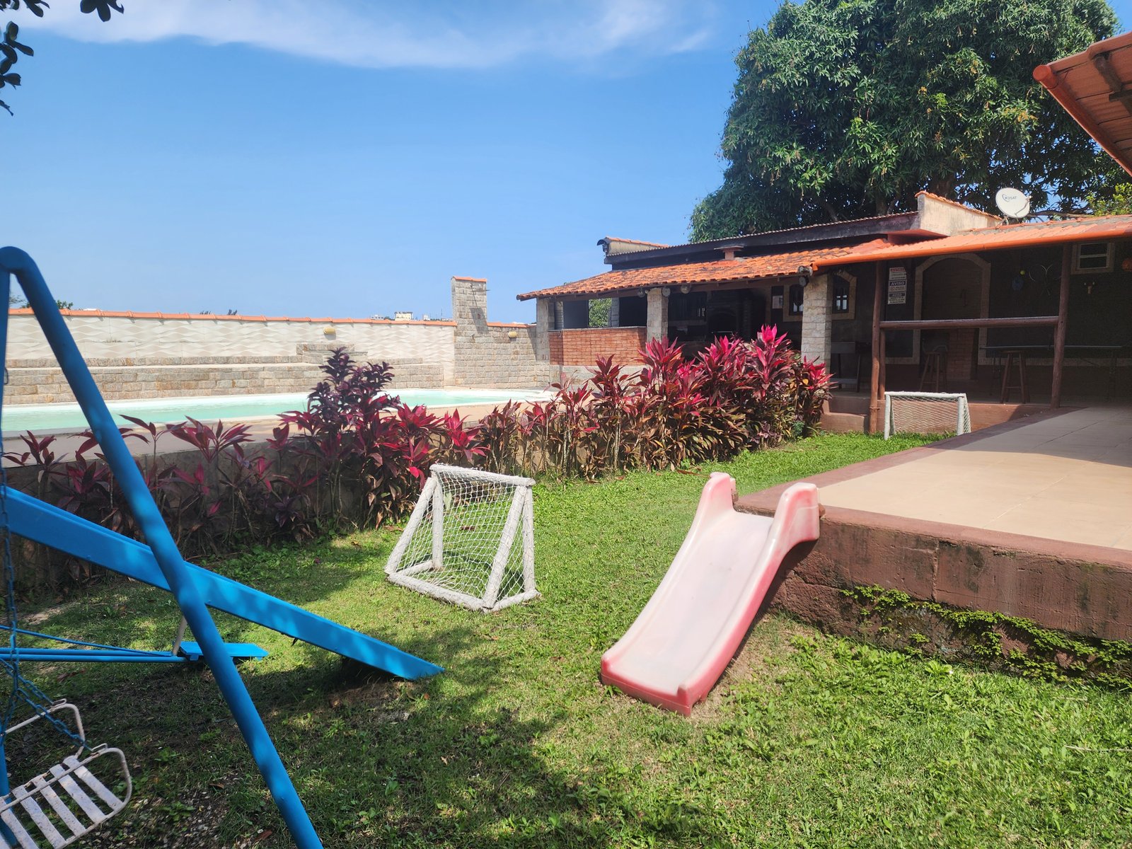 Jardim com brinquedos infantis junto à piscina