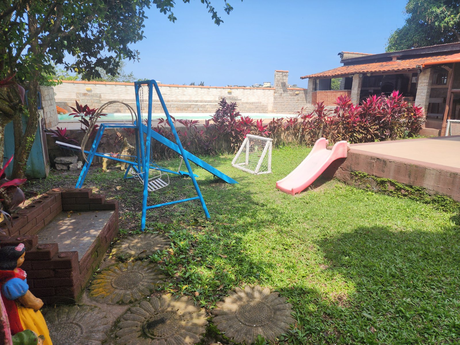 Jardim da casa com balanço, escorregador e golzinho