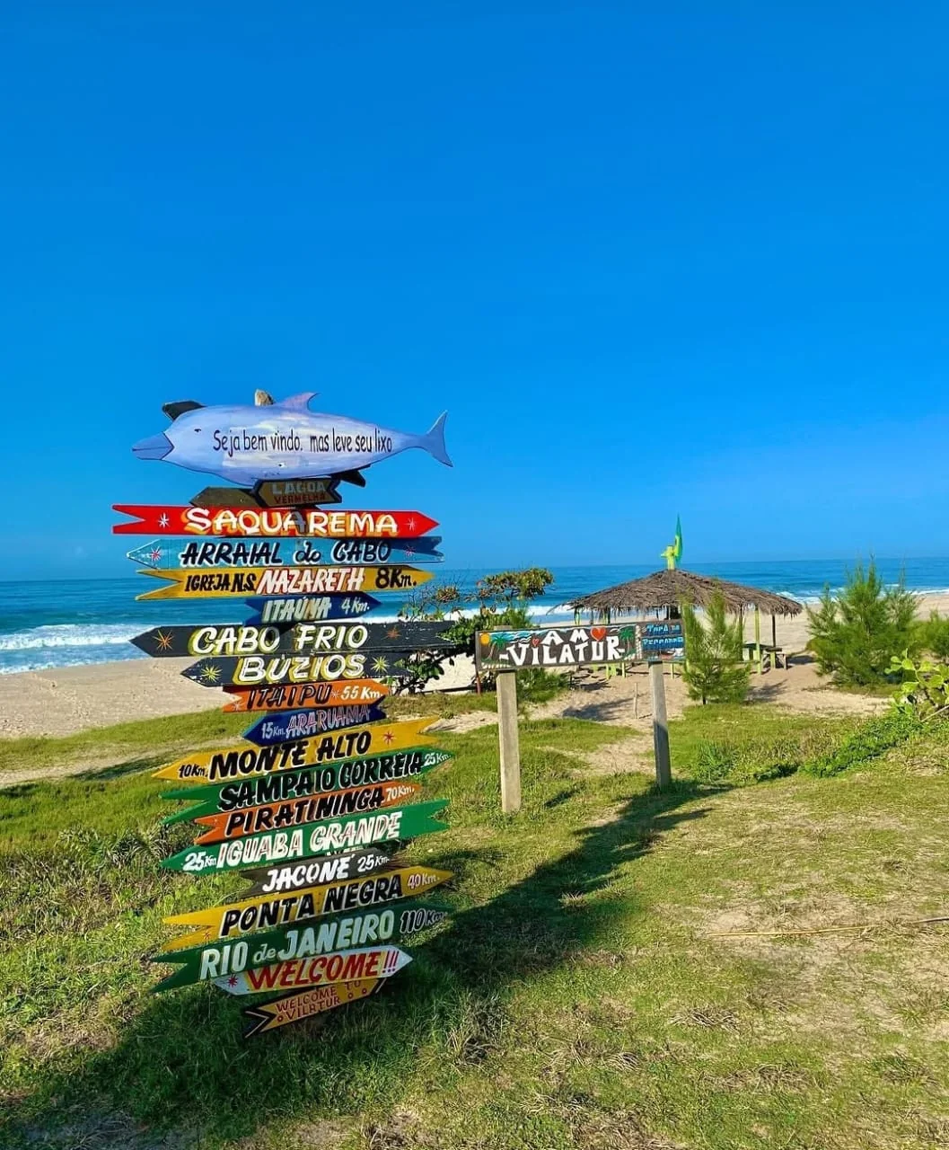 Placas coloridas indicando destinos na praia do Balneário de Vilatur, Saquarema
