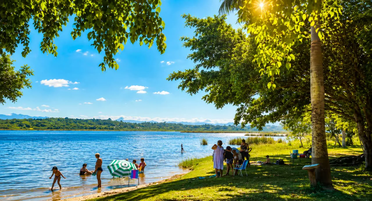Lagoa cercada por árvores e famílias em um dia ensolarado