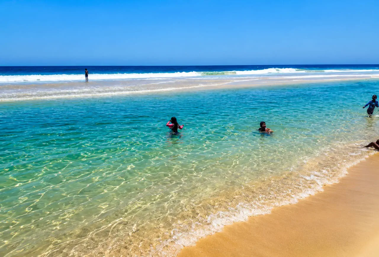 Banhistas nas águas transparentes da praia